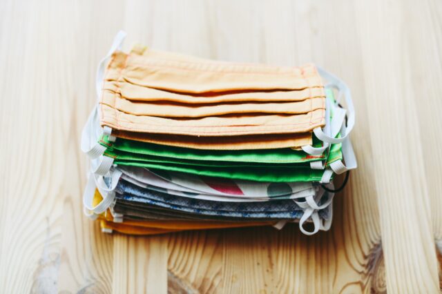 A stack of colored face masks on a wooden table.