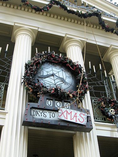 A clock on the side of a building with christmas decorations.