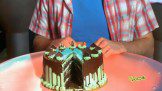 A man cutting into a chocolate cake.