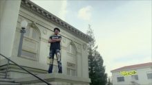 A man in black outfit standing on a block of a building