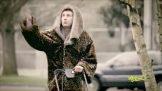 A man in a leopard coat riding a bike.