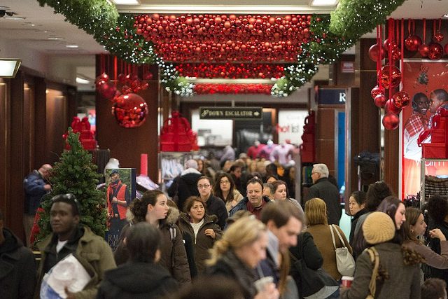 A crowd of people in a shopping mall with christmas decorations.