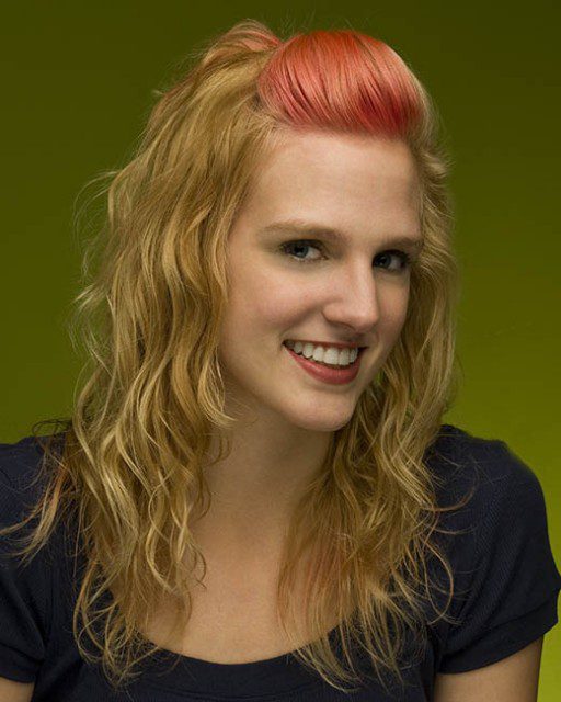 A woman with long curly hair and pink hair.