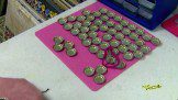 A bunch of bottle caps arranged on a pink board