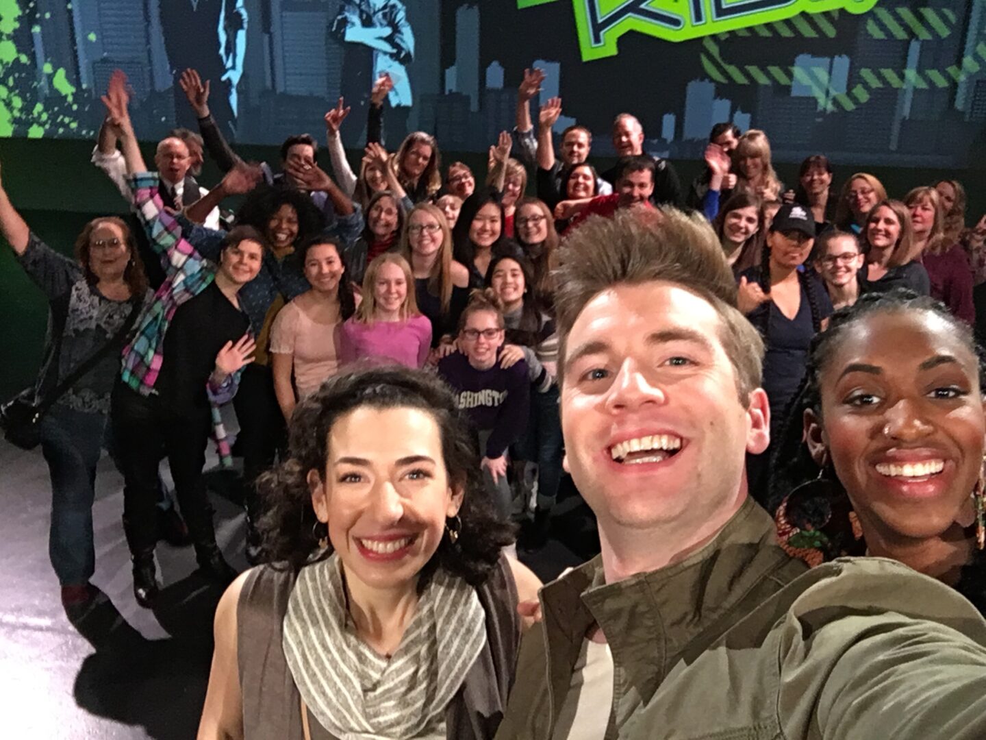 A group of people posing for a selfie in front of a green screen.