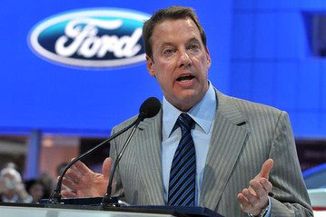 A man speaking at a podium in front of a ford logo.