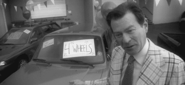 A man standing next to a car with a sign on it.