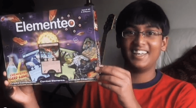 A young boy holding up a box of elemento.