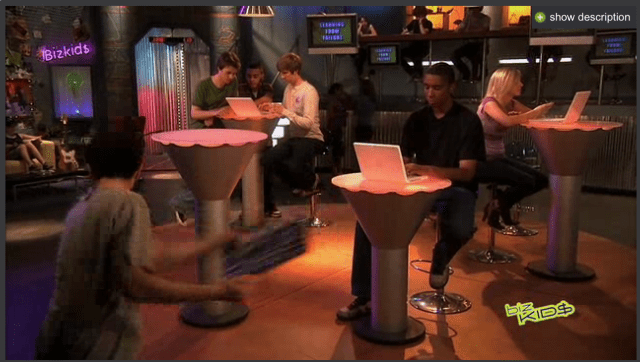 A group of people sitting around a table with laptops.