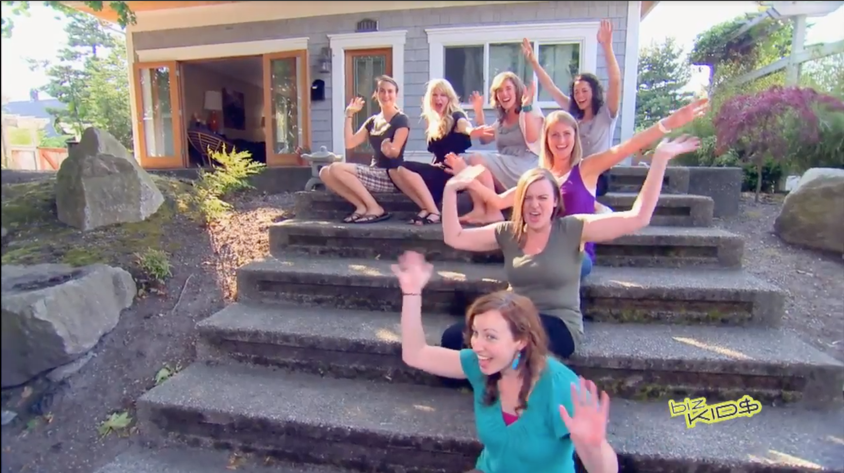A group of people posing on steps in front of a house.