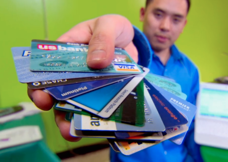 A man holding up a bunch of credit cards.