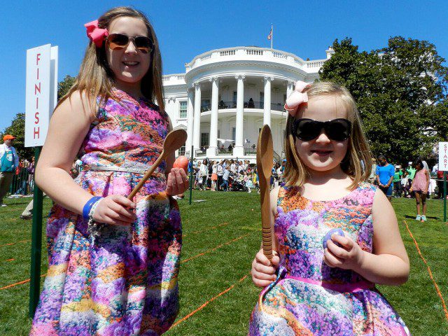 Two girls in dresses standing in front of the white house.