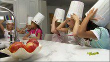 Six little girls wearing chef caps in a kitchen