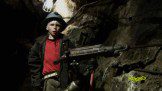 A boy is holding a machine in a cave.
