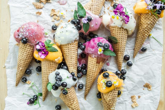 A group of ice cream cones with berries and flowers.