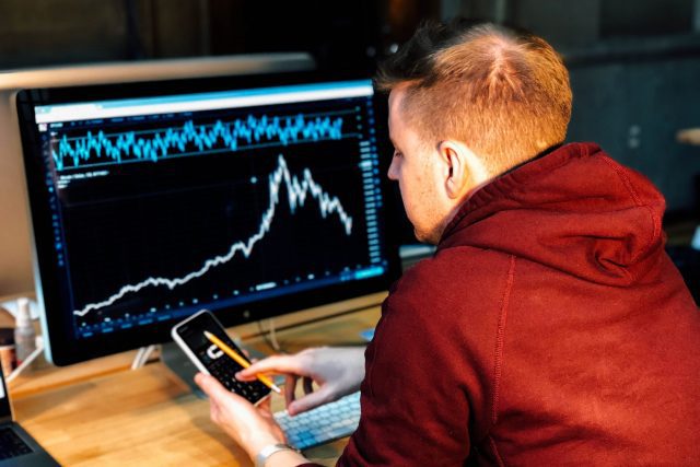 A man looking at a stock chart on a computer screen.