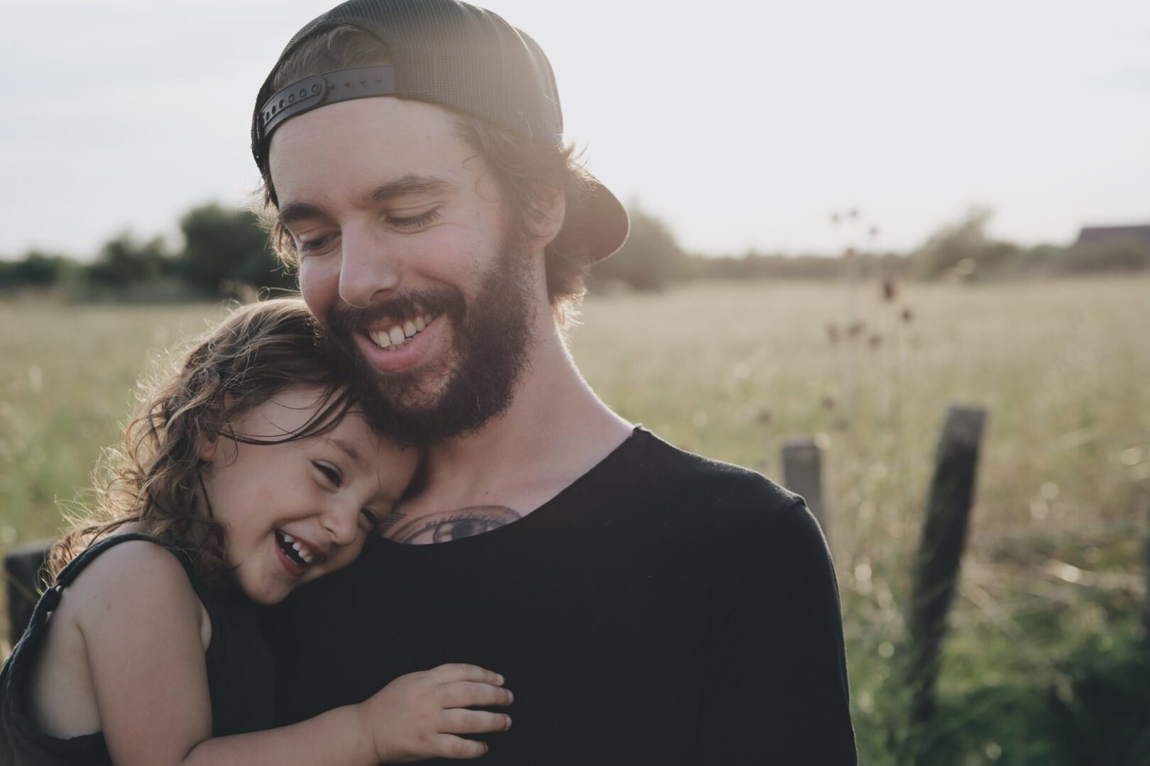 A man with a beard and a little girl in a field.