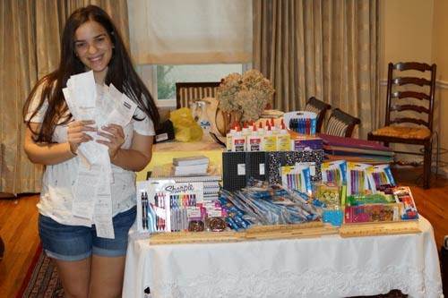 A young girl standing in front of a table full of supplies.