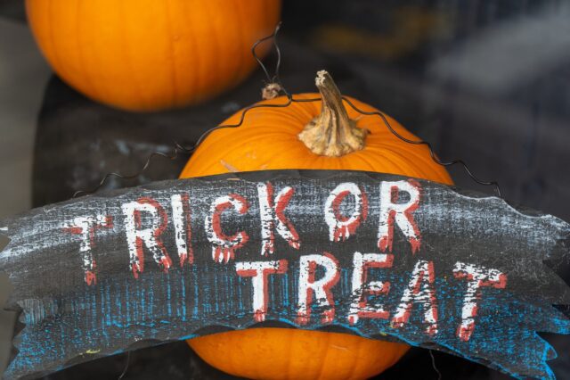 A sign that says trick or treat on a window display.