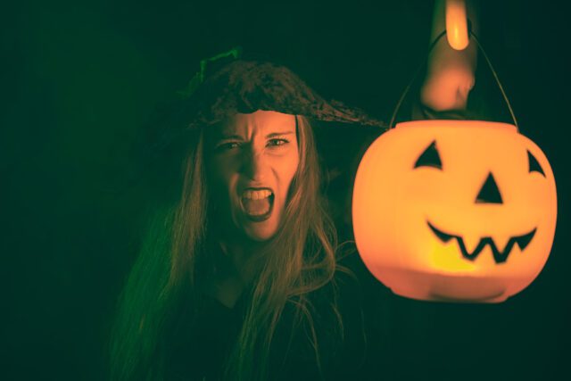 A girl wearing a Halloween dress holding a pumpkin