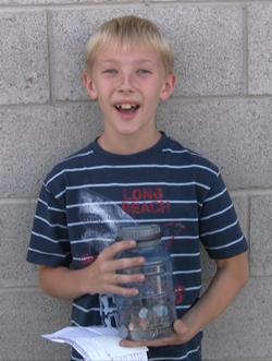 A young boy holding a jar of coins.