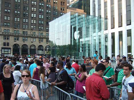 A crowd of people standing in front of an apple store.