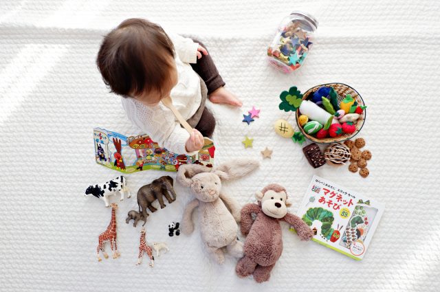A baby is playing with stuffed animals on a bed.