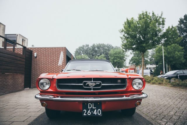 A red ford mustang parked in front of a brick building.
