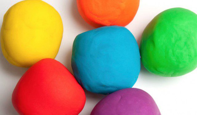 A group of colorful play dough balls on a white surface.