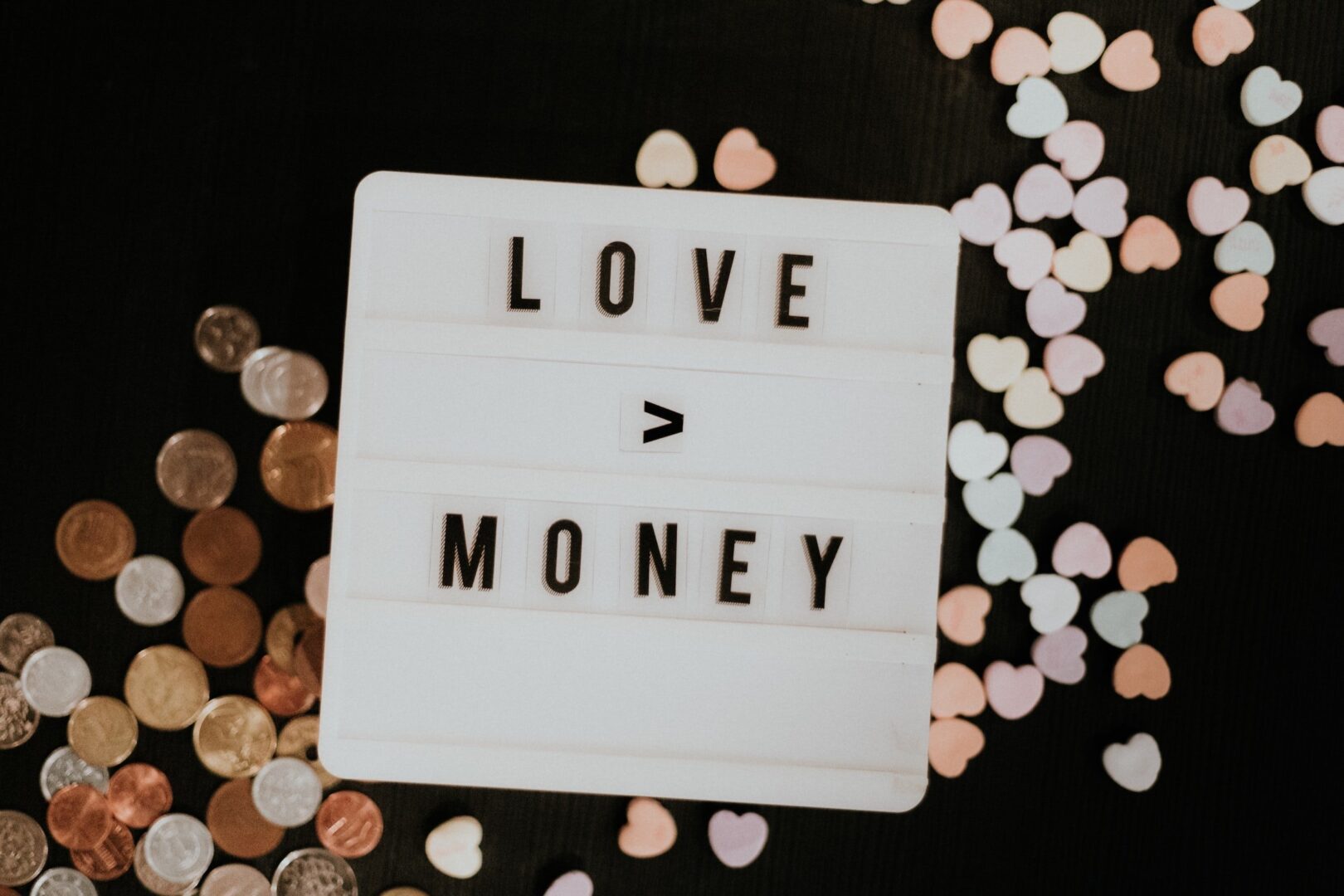 A light box with the words love money surrounded by confetti.