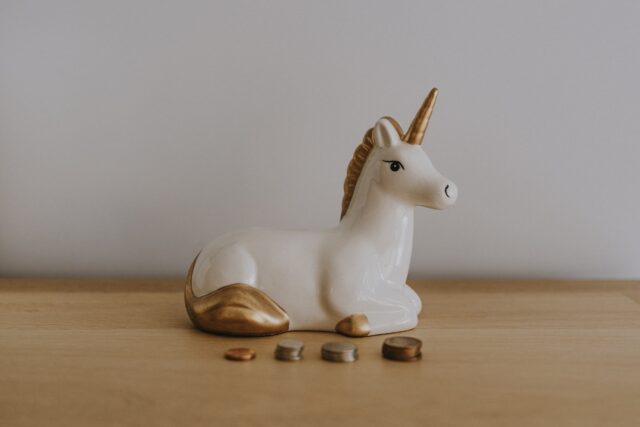A ceramic unicorn sitting on a wooden table.