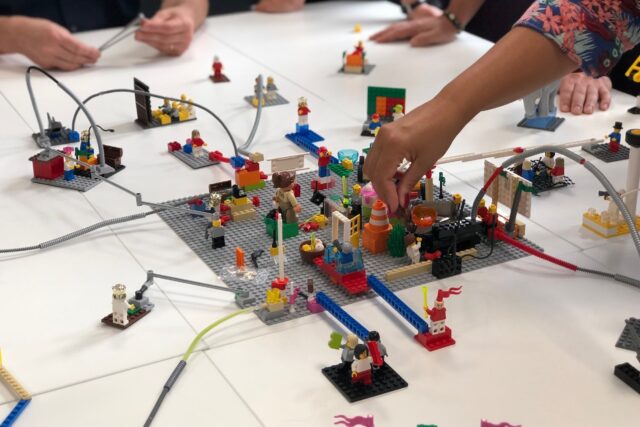 A group of people playing with legos on a table.